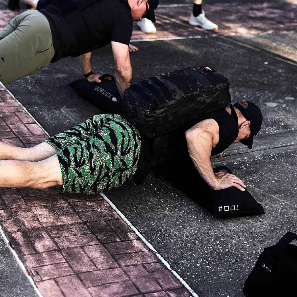 Man doing outdoor push-ups wearing GORUCK rucksack, camo shorts, fitness training