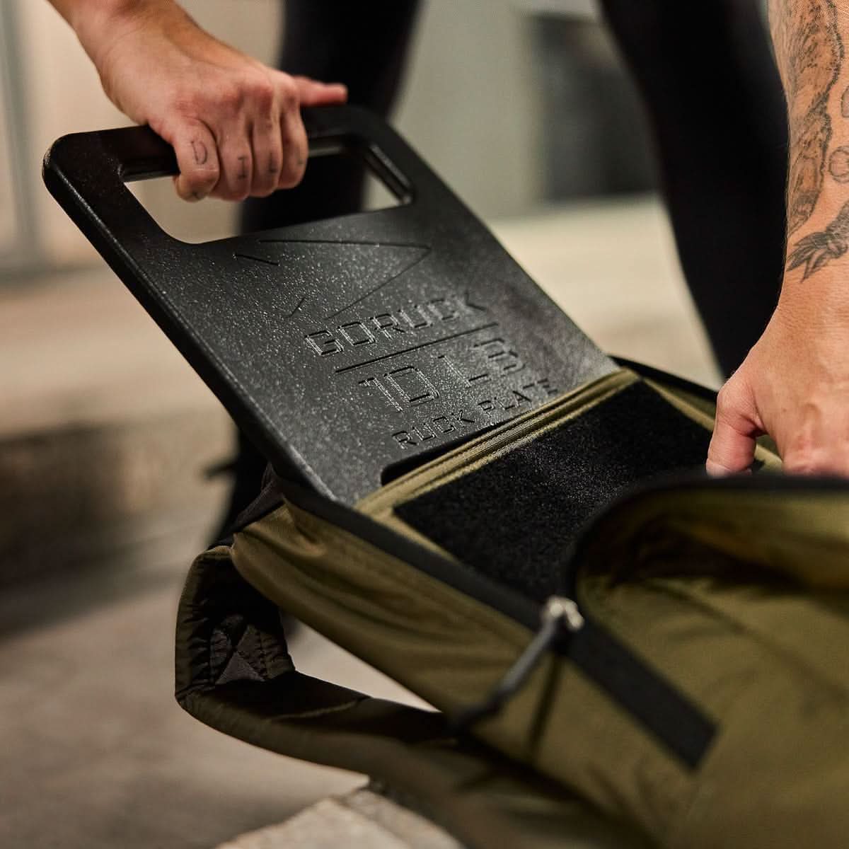 GORUCK ruck plate being placed into a rucksack for rucking fitness training
