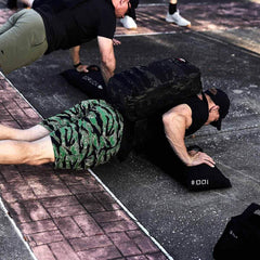 Man doing outdoor push-ups wearing GORUCK rucksack, camo shorts, fitness training
