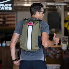 Man wearing sunglasses and a gray shirt, giving a thumbs up, carrying the Basic Rucker—ready for some serious rucking.