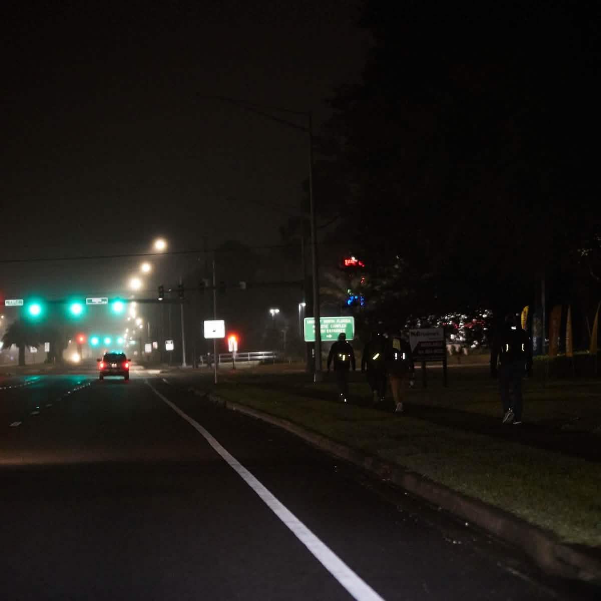 People wearing GORUCK reflective ruck bands walking on a city street at night