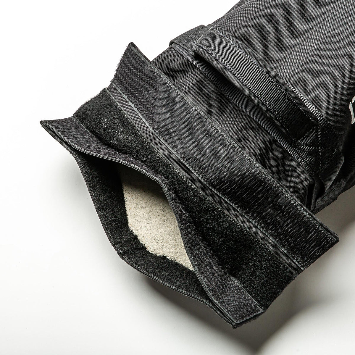 Close-up of a Simple Training Sandbags black fabric pouch with Velcro straps, partially open to reveal a soft, light-colored lining—perfect for home gym workouts.