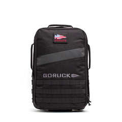The Rucker 5.0 is a black GORUCK rucksack featuring an American flag patch, front handles, MOLLE webbing on the lower front, and built-in lumbar support for comfortable rucking.